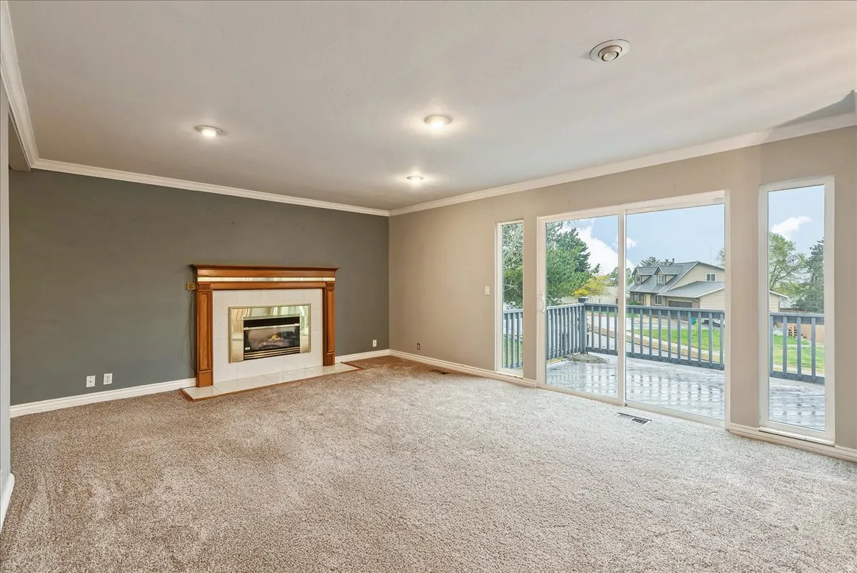 Unfurnished living room with carpet flooring, a fireplace, and ornamental molding
