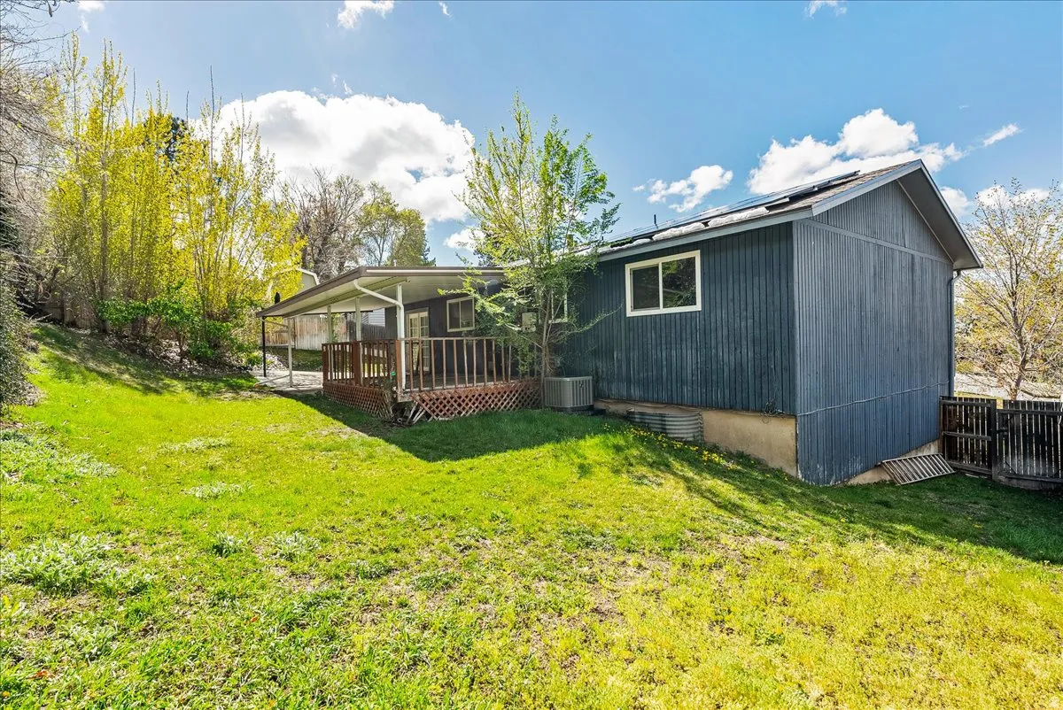 Rear view of house featuring a deck, a yard, and roof mounted solar panels