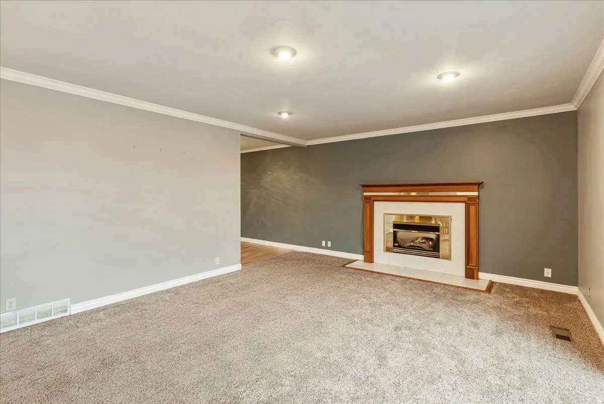 Unfurnished living room featuring ornamental molding, light colored carpet, and a fireplace