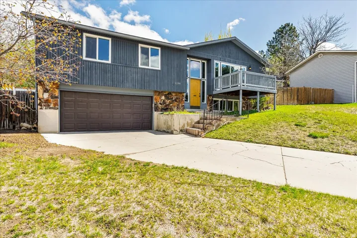 Raised ranch with a garage, concrete driveway, and stone siding