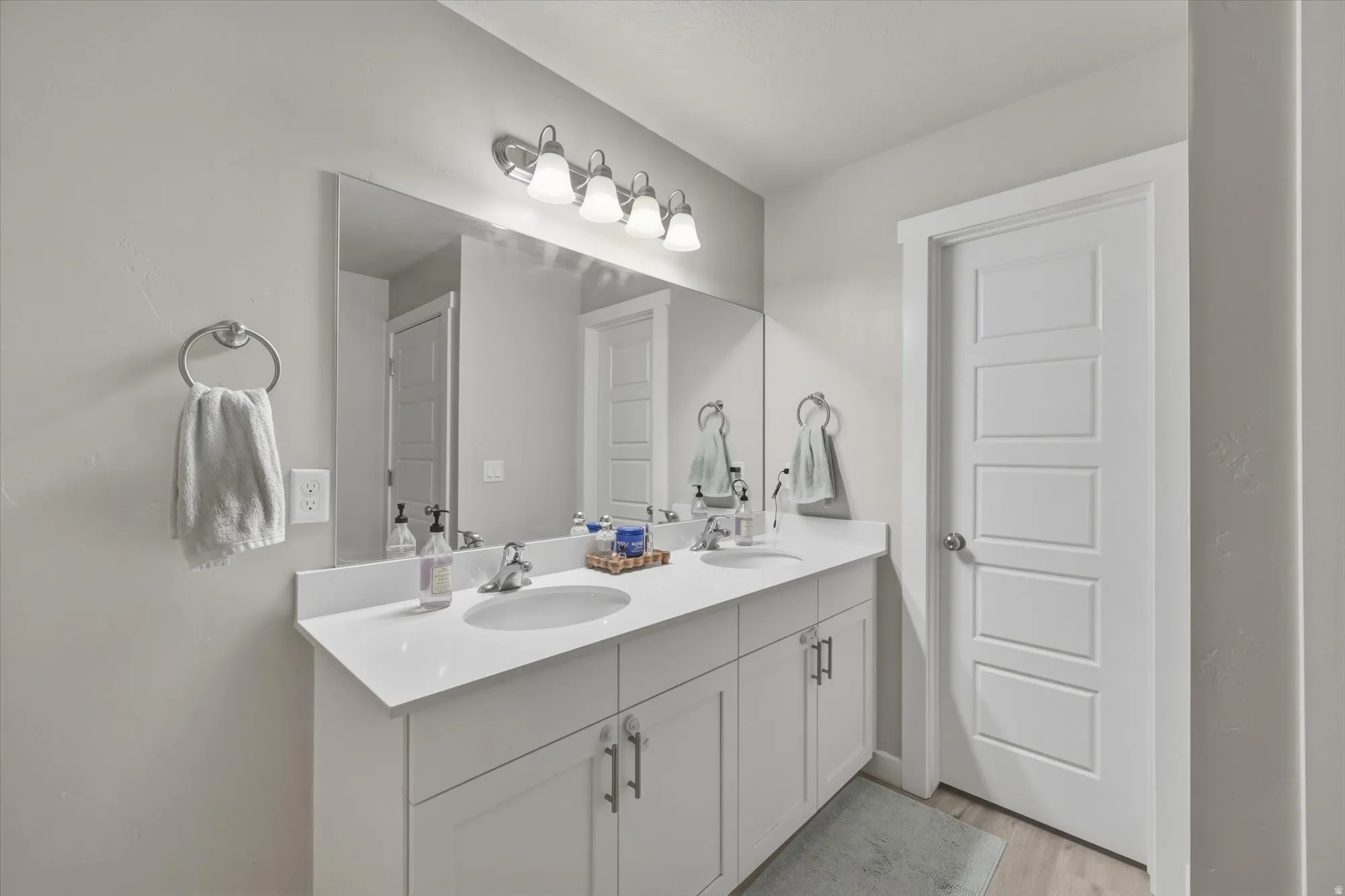 Full bath with double vanity and light wood-style floors