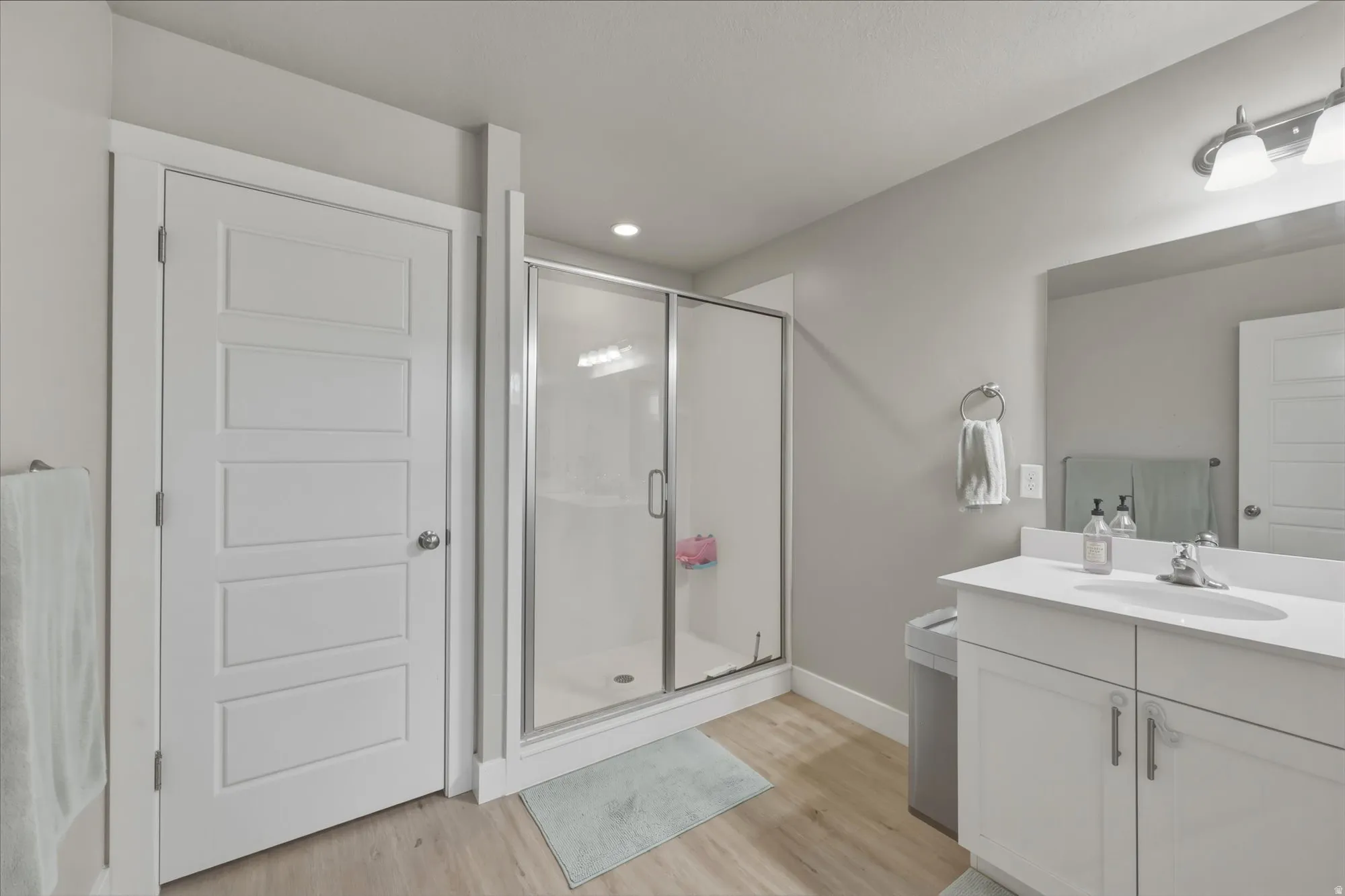 Full bath featuring vanity, a shower stall, light wood-style flooring, and recessed lighting