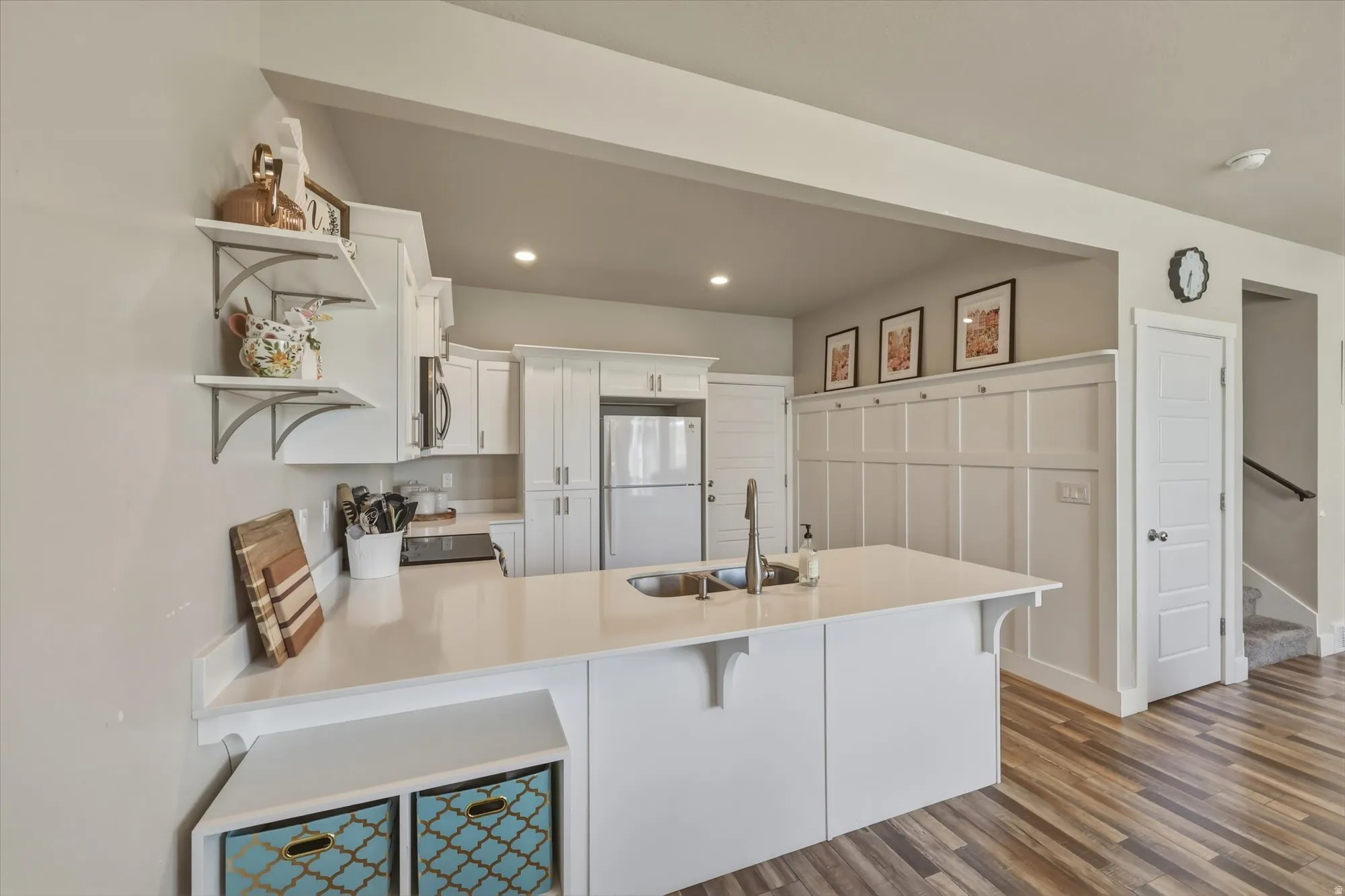 Kitchen with open shelves, white cabinets, freestanding refrigerator, a breakfast bar area, and a peninsula