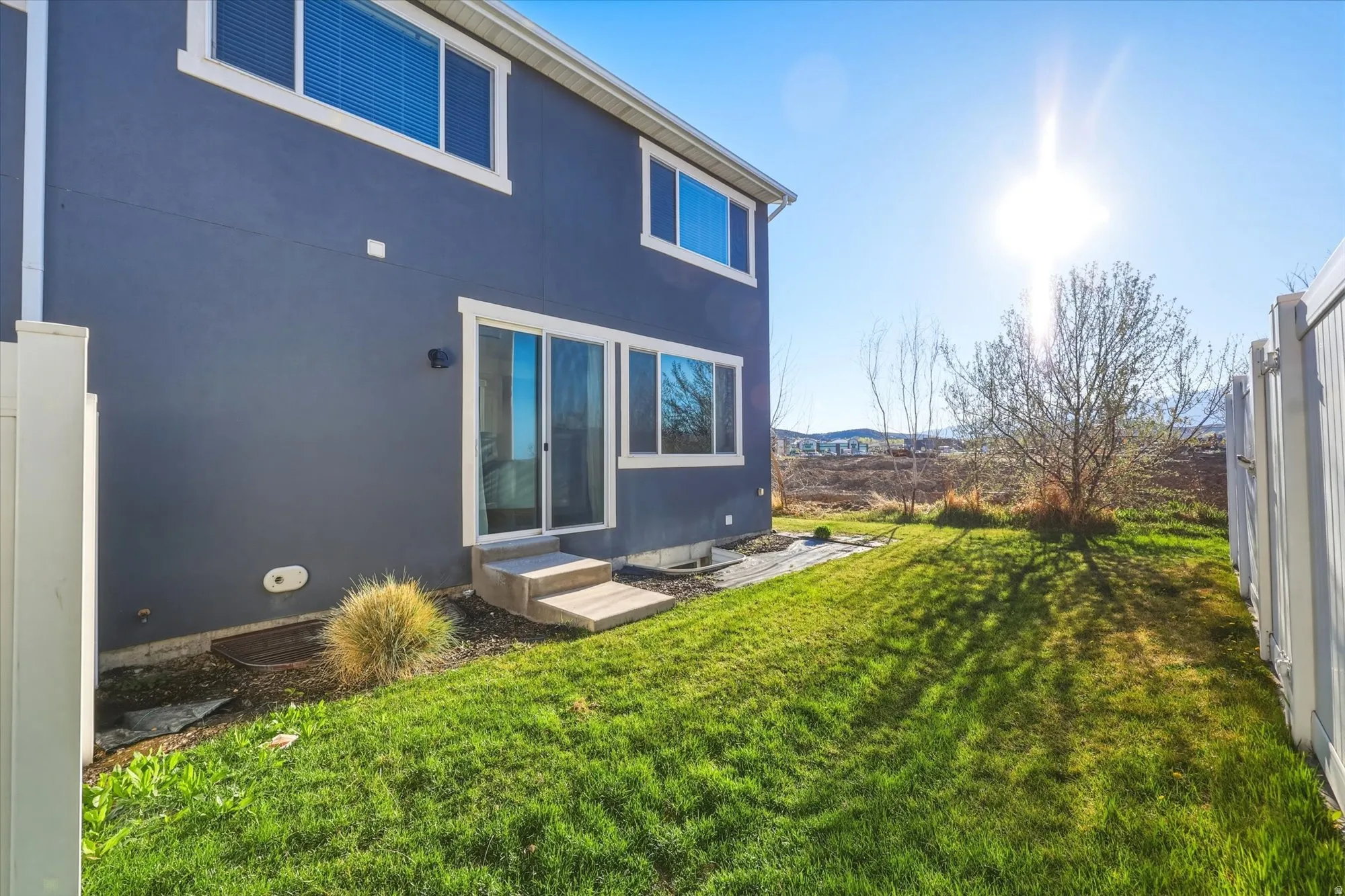 Rear view of property featuring a lawn, stucco siding, and entry steps