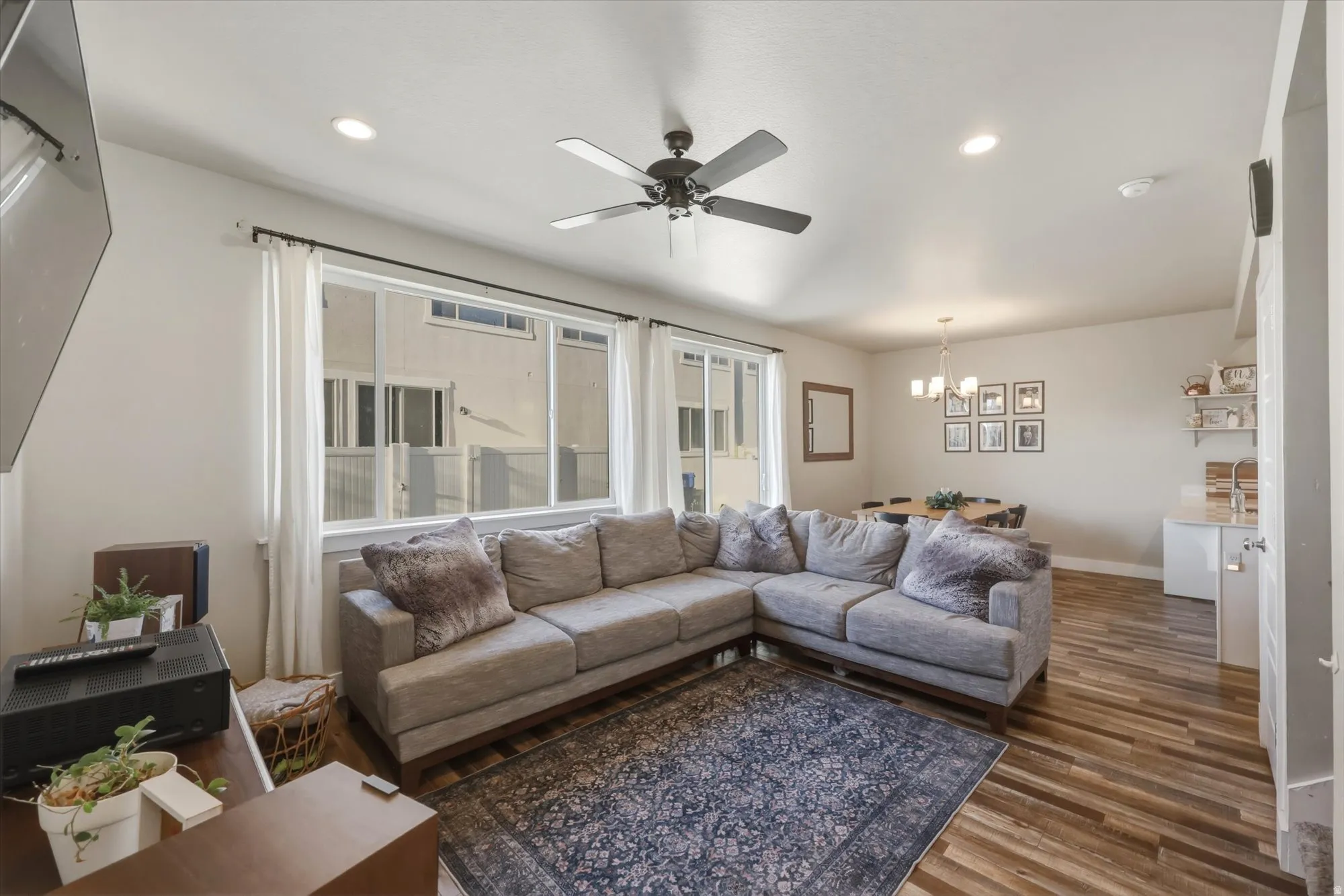 Living area featuring a chandelier, ceiling fan, and dark wood-type flooring