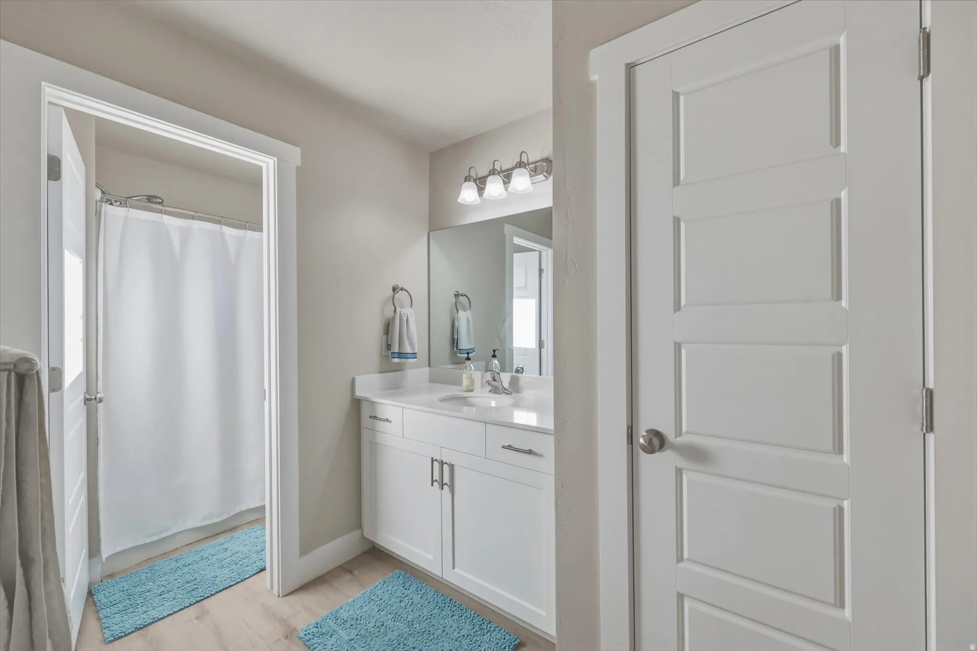 Full bathroom with vanity, curtained shower, and light wood-style floors