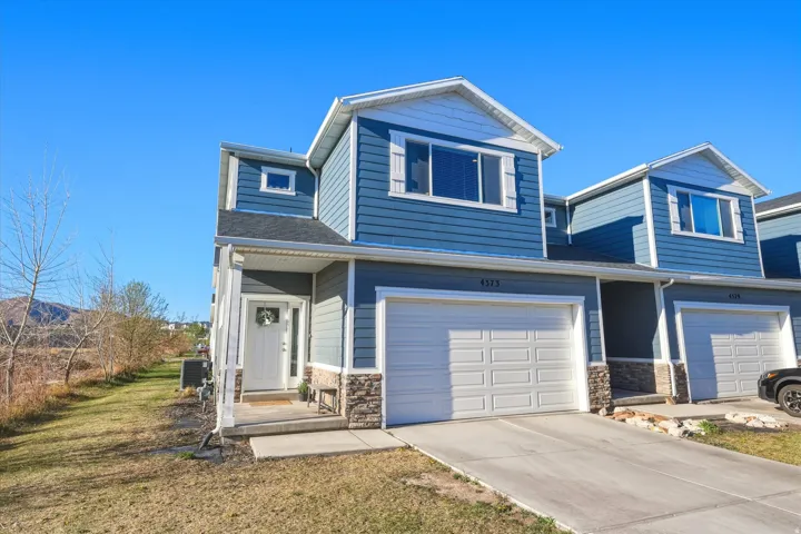 View of front of property with stone siding, a garage, and driveway