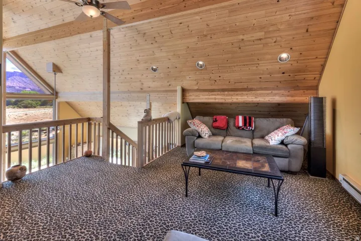 Living room featuring a vaulted wooden ceiling, carpet floors, a ceiling fan, baseboard heating, and recessed lighting