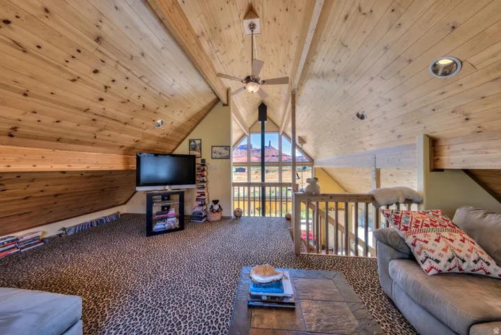 Carpeted living room featuring a wood ceiling with exposed beams and a ceiling fan