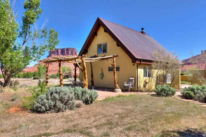 Back of property with a patio, a metal roof, a lawn, stucco siding, and a pergola