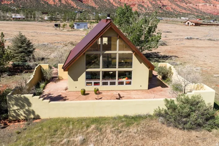 Back of property with a mountain view, a chimney, stucco siding, and a view of countryside