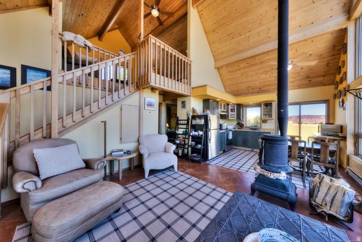 Living room featuring a high wood beamed ceiling, a wood stove, and a ceiling fan