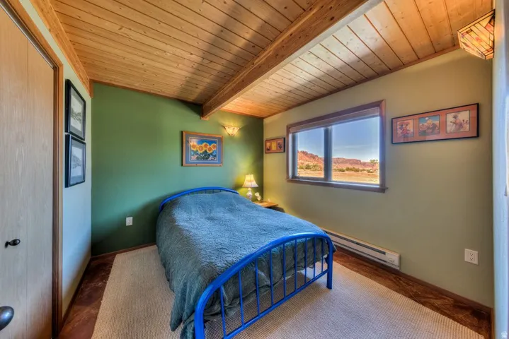 Bedroom with a wood ceiling with exposed beams, baseboard heating, and a closet