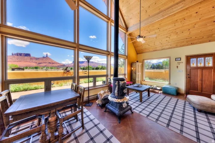 Sunroom with a mountain view, a wood stove, and a vaulted wood ceiling