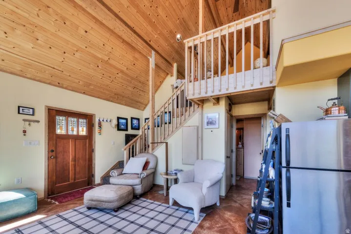 Tiled living area with stairs and a vaulted wooden ceiling