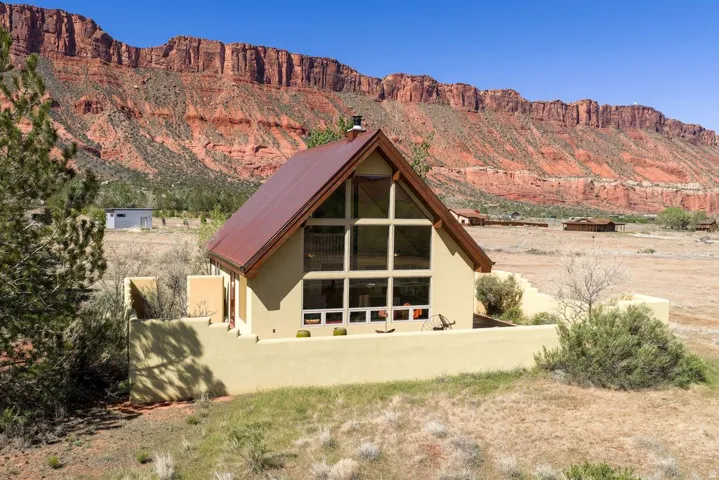 Back of house with a mountain view, a chimney, and stucco siding