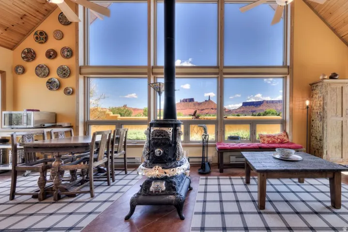 Living area with a ceiling fan, a vaulted wood ceiling, a wood stove, a mountain view, and baseboard heating