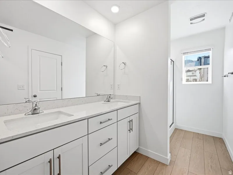 Primary en-suite bathroom with double vanity, a shower stall, and water closet