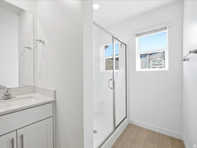 Primary en-suite bathroom with double vanity, a shower stall, and water closet