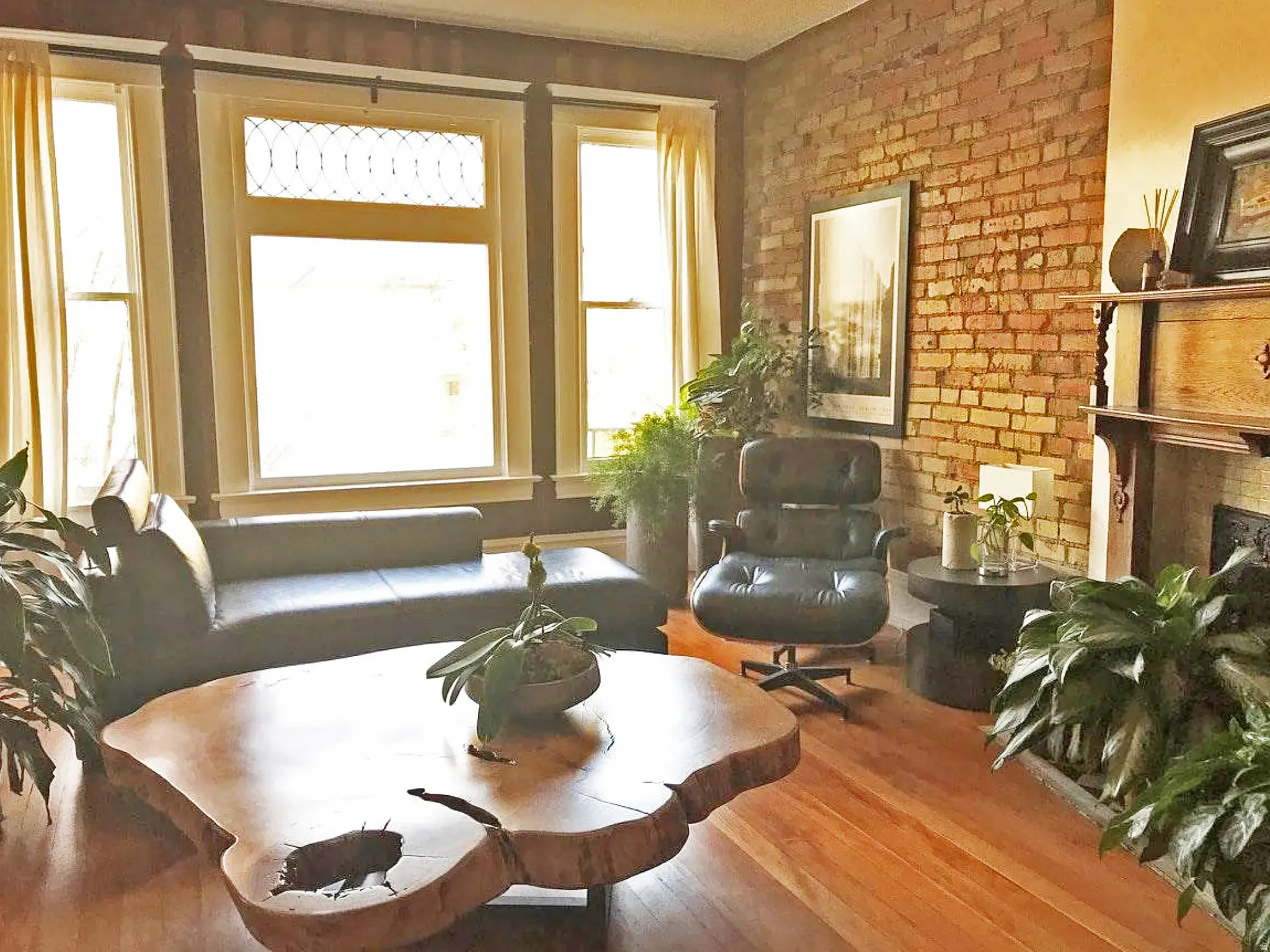 Living room with wood-type flooring, a fireplace, and brick wall
