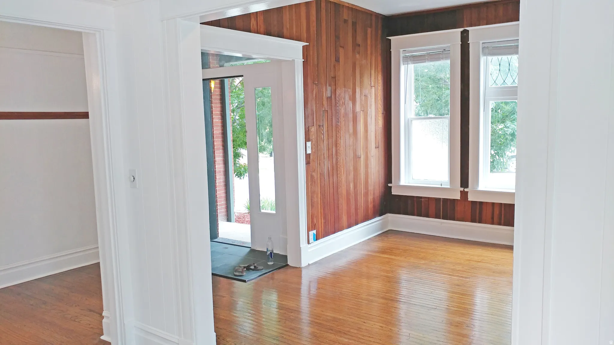 Foyer with light wood-type flooring and wood walls