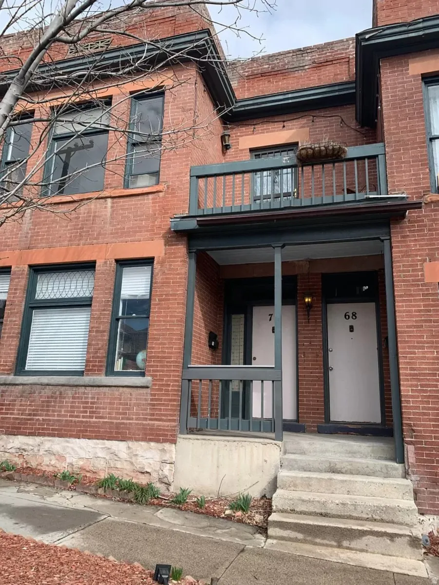 Doorway to property featuring brick siding and a porch