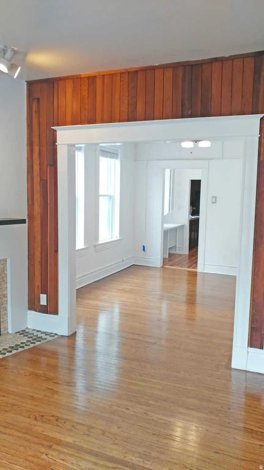 Unfurnished living room with wood walls and light wood finished floors