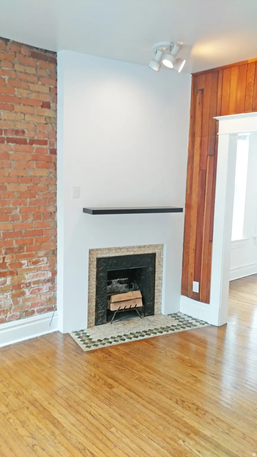 Detailed view of wood finished floors, a fireplace with flush hearth, and wood walls
