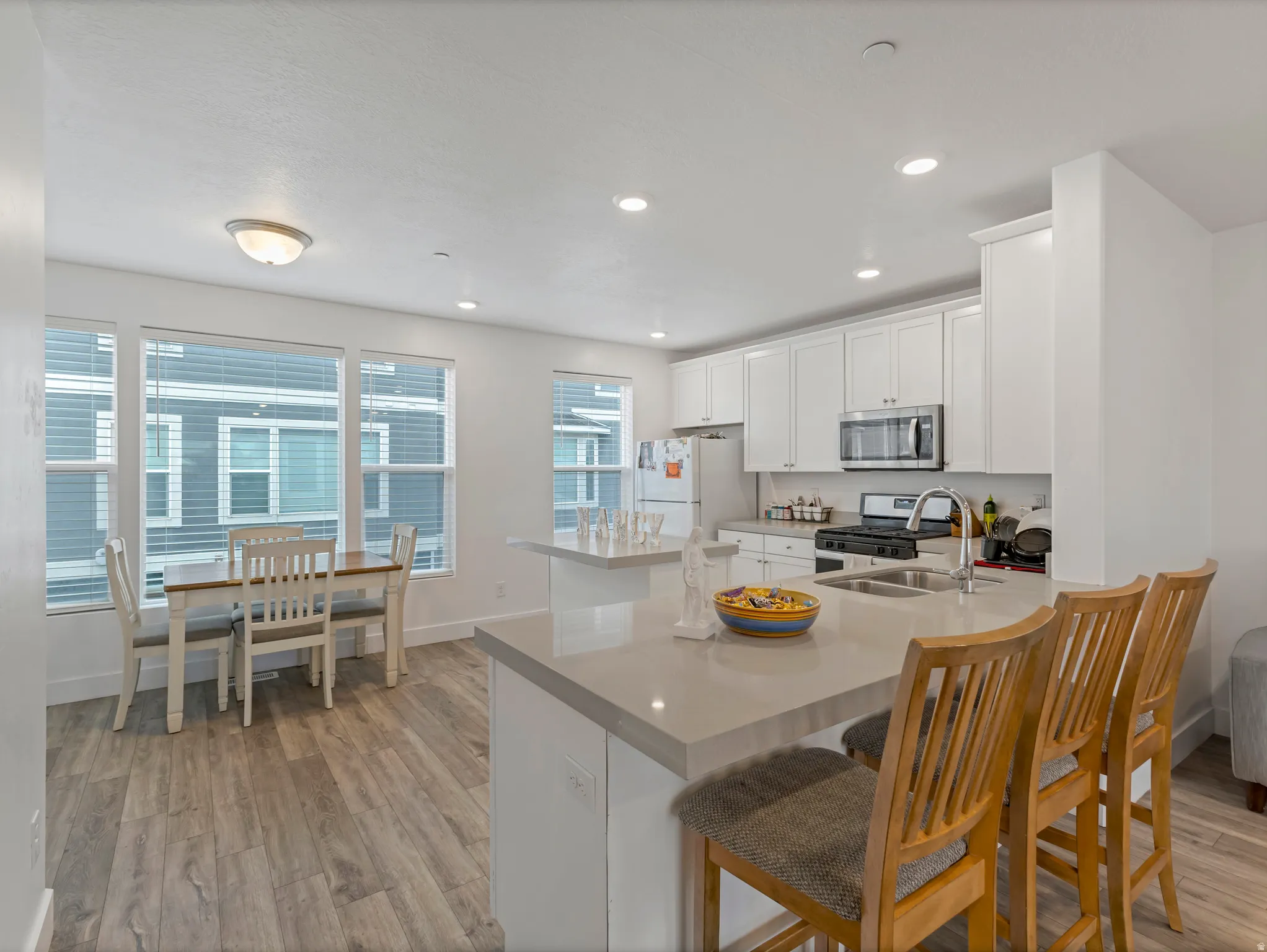 Kitchen featuring white cabinetry, light wood-style flooring, a breakfast bar area, stainless steel appliances, and a peninsula