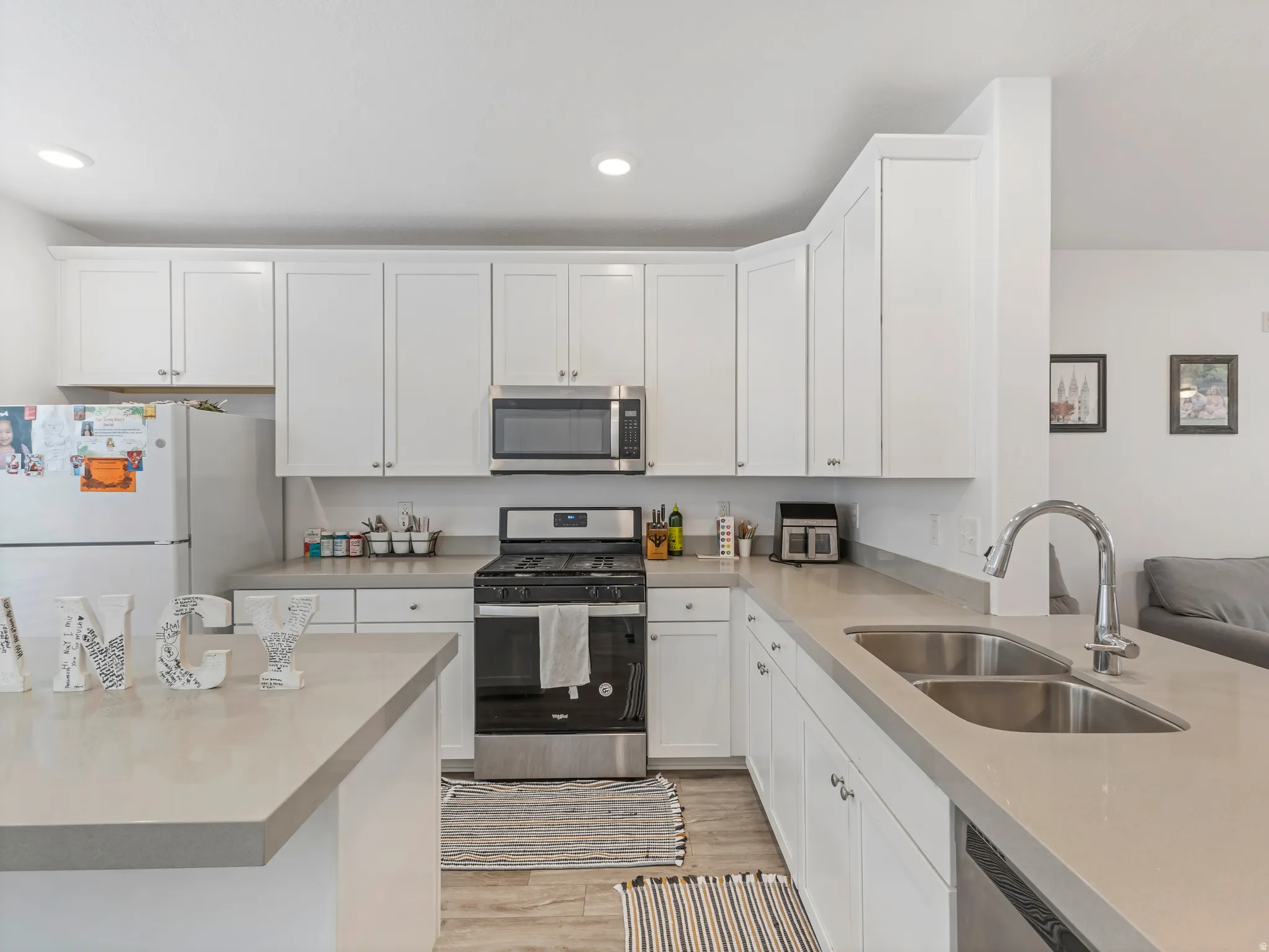 Kitchen with stainless steel appliances, white cabinetry, light wood-style floors, and recessed lighting