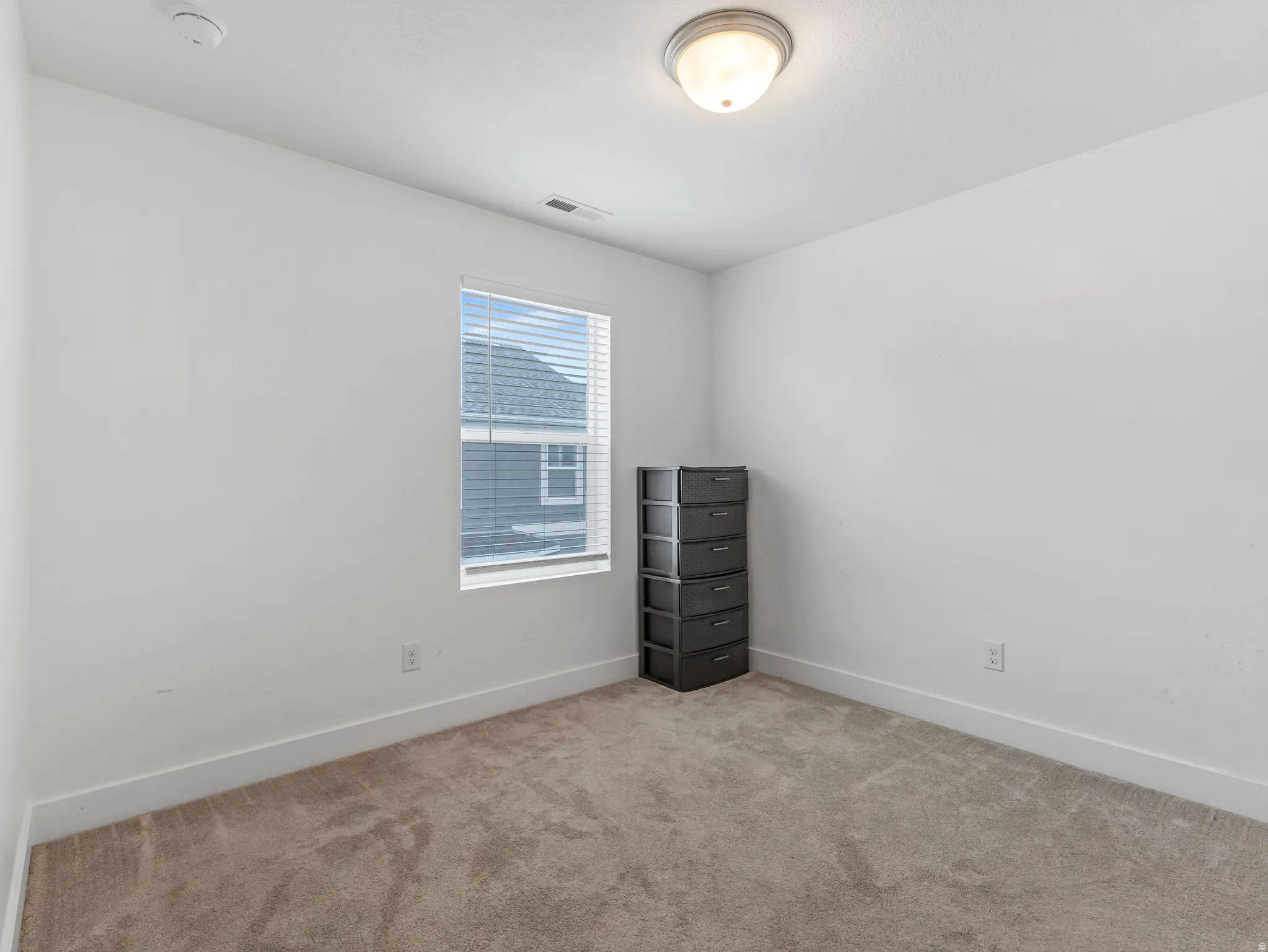 Carpeted spare room featuring baseboards