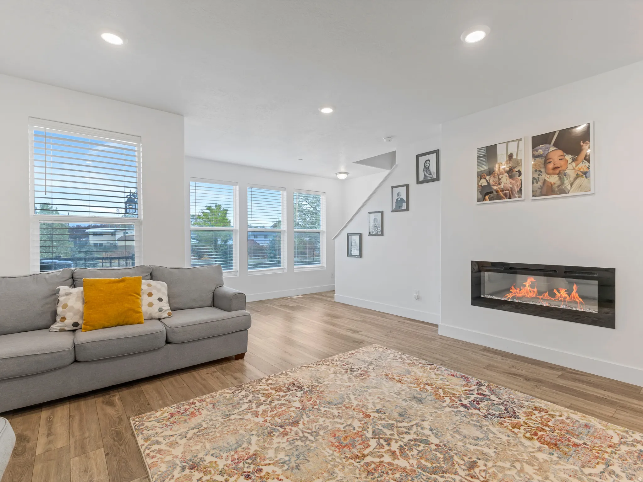 Living area with light wood-type flooring, a glass covered fireplace, and recessed lighting