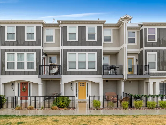 View of front facade with a fenced front yard, stucco siding, and a balcony