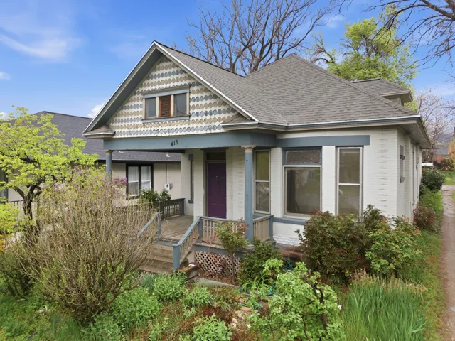 Victorian home with a porch, brick siding, and roof with shingles