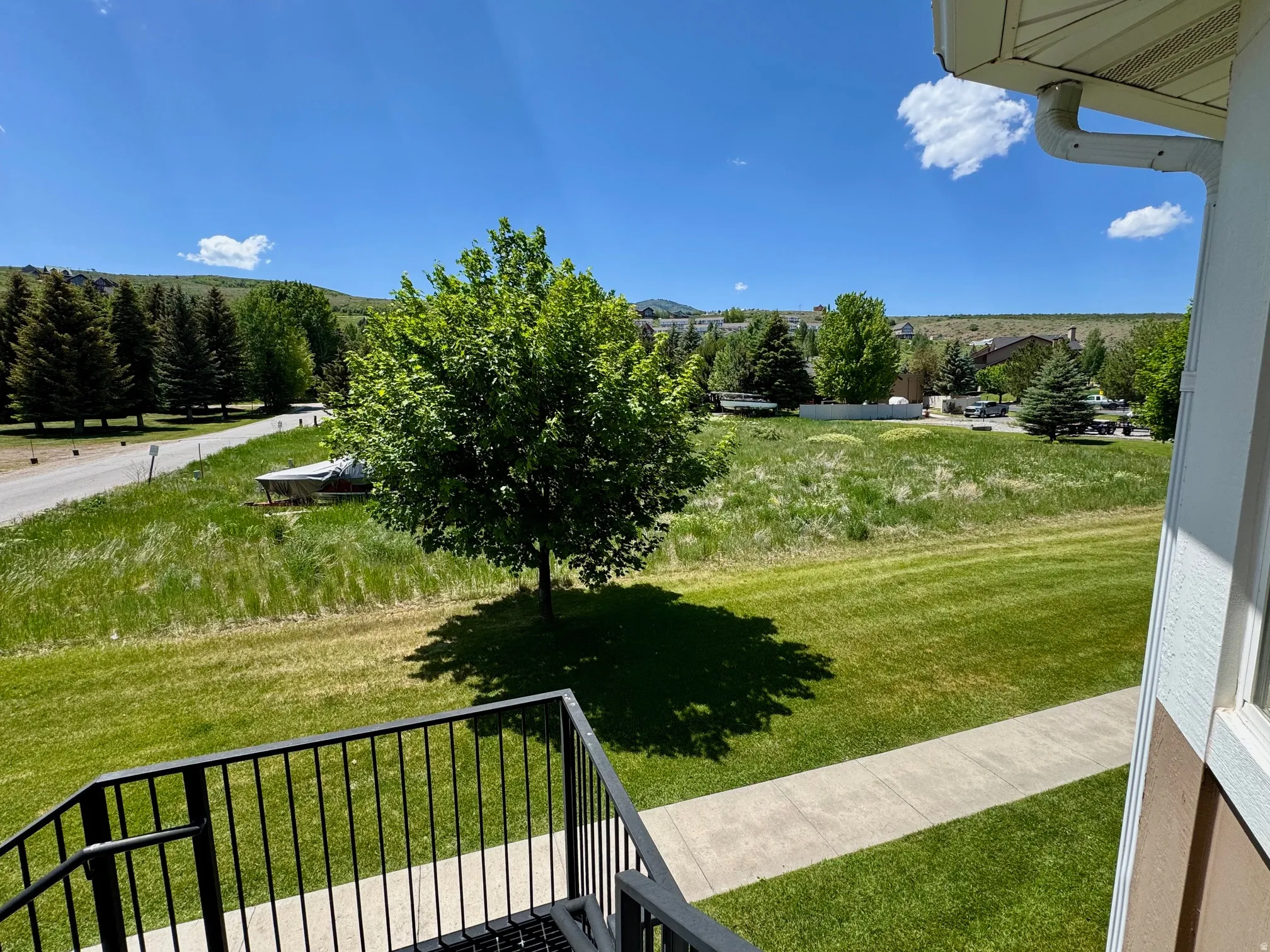View of green lawn featuring a view of countryside and a balcony