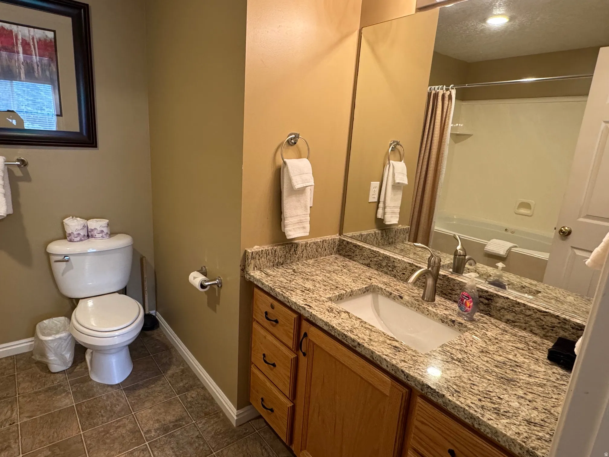 Bathroom featuring vanity, dark tile patterned floors, and shower / bath combo with shower curtain