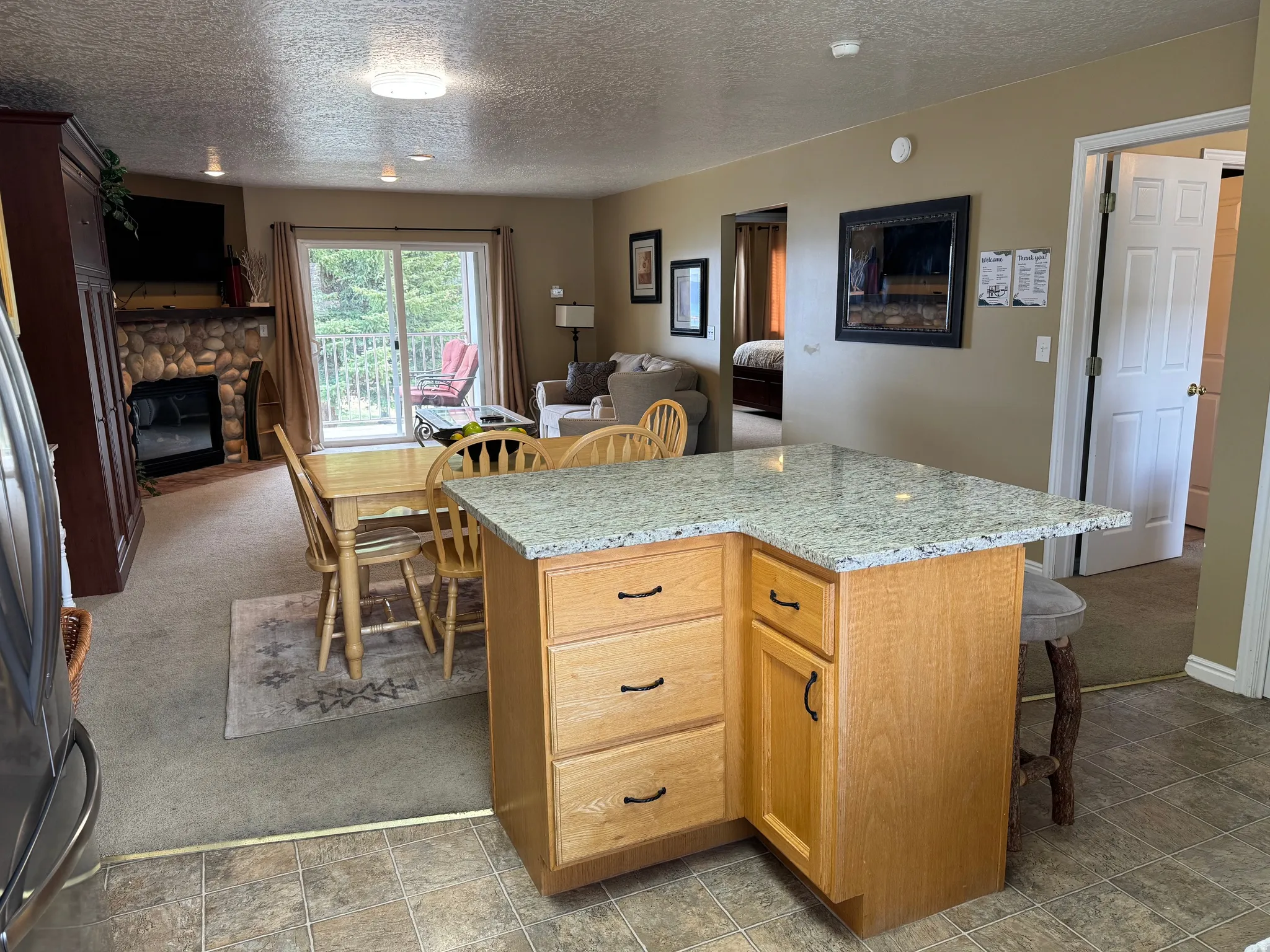 Kitchen with open floor plan, dark colored carpet, a center island, a breakfast bar area, and stainless steel refrigerator