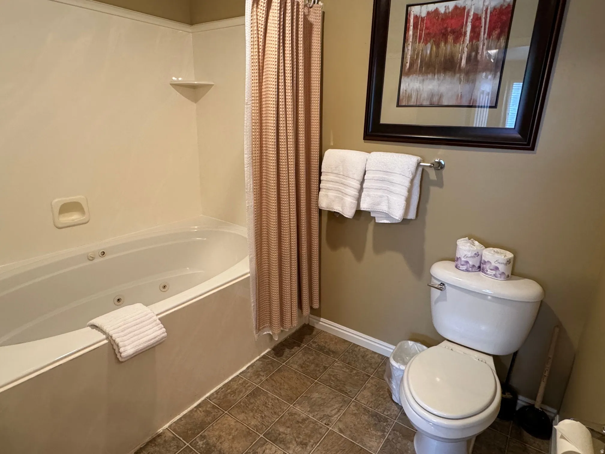 Bathroom featuring a combined bath / shower with jetted tub and toilet