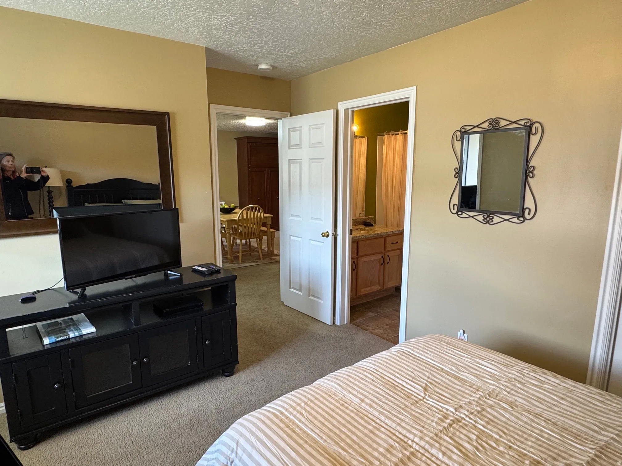 Bedroom featuring dark carpet, a textured ceiling, and connected bathroom