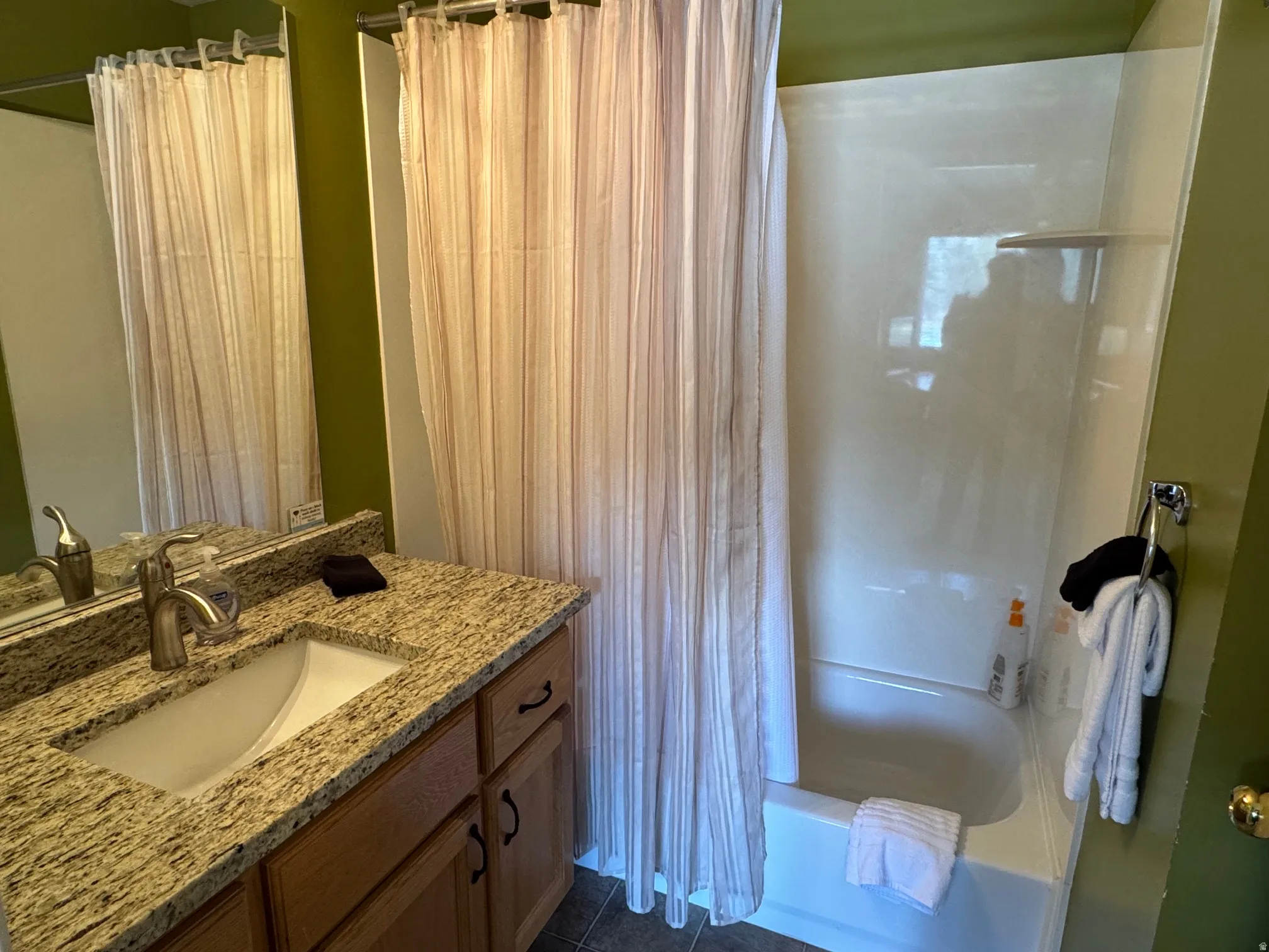 Bathroom featuring vanity, shower / bath combo, and dark tile patterned flooring