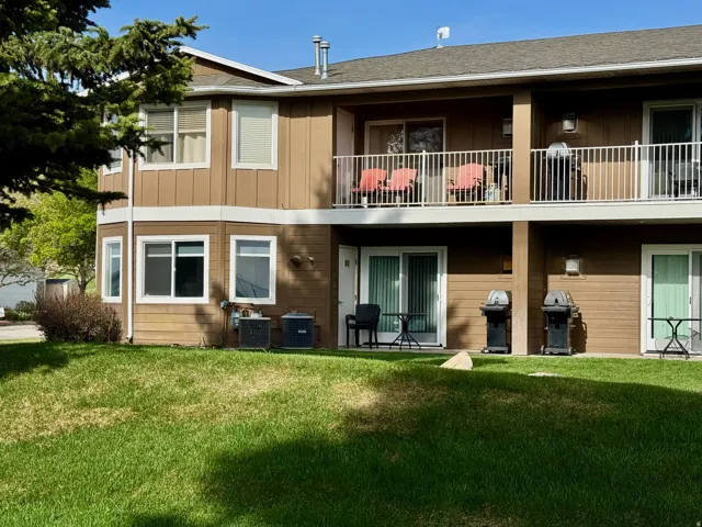 Back of house featuring a balcony, a patio area, a yard, and board and batten siding