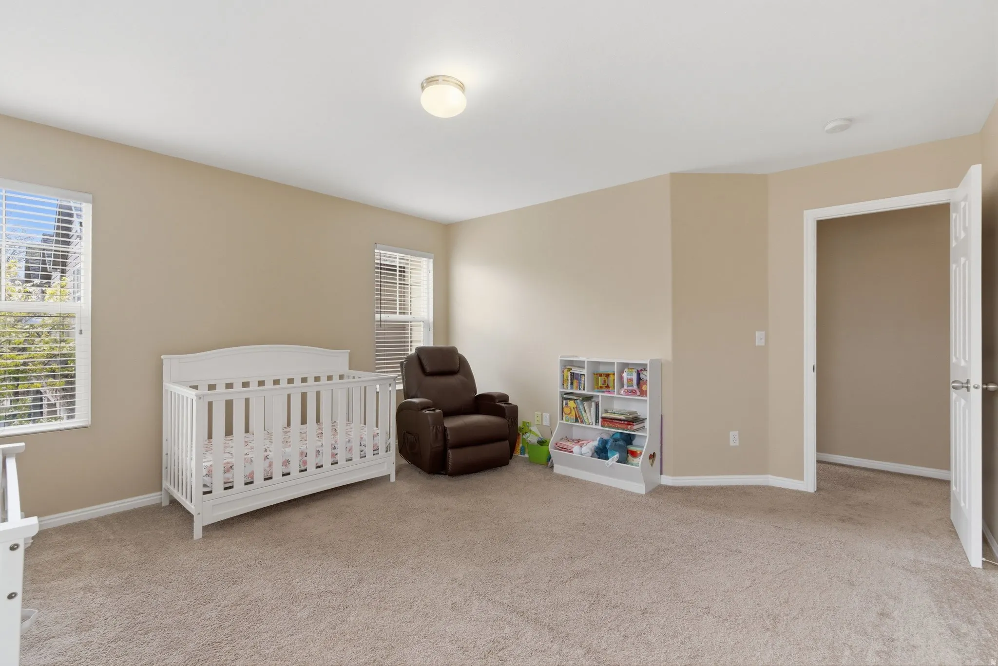 Bedroom featuring a crib and light carpet