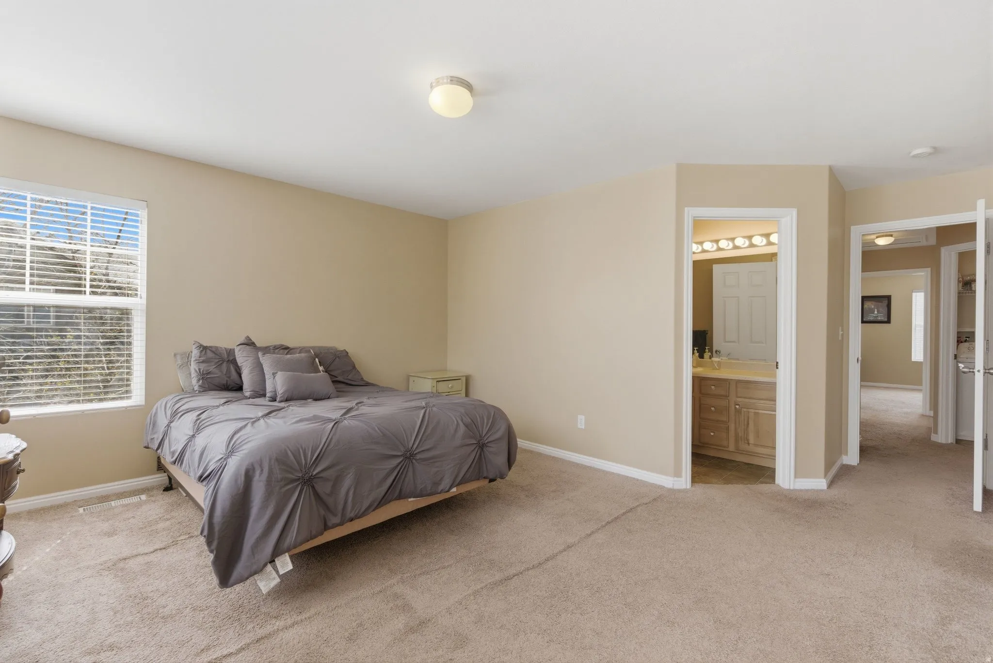 Bedroom featuring light carpet and connected bathroom