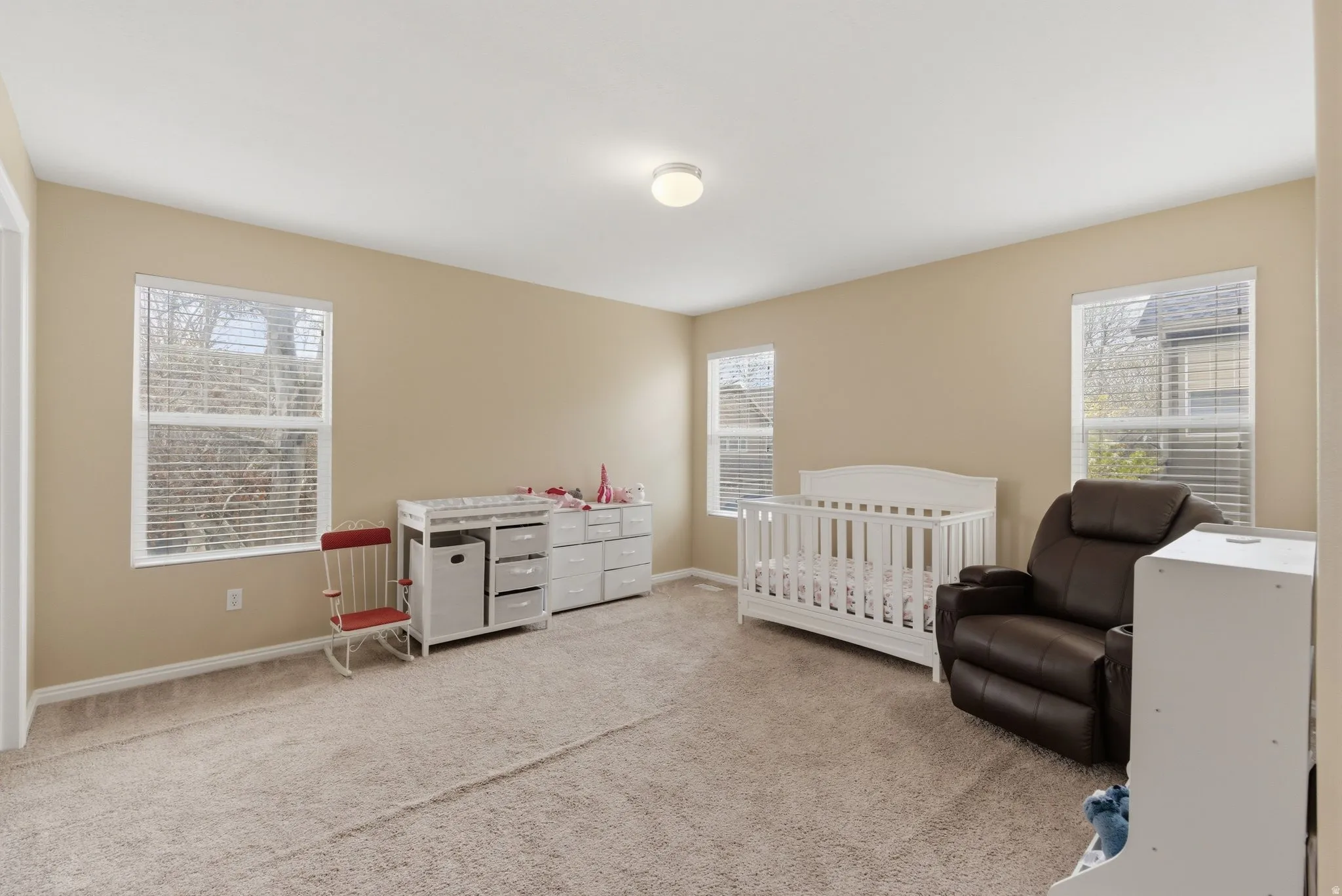 Bedroom featuring a nursery area and light carpet