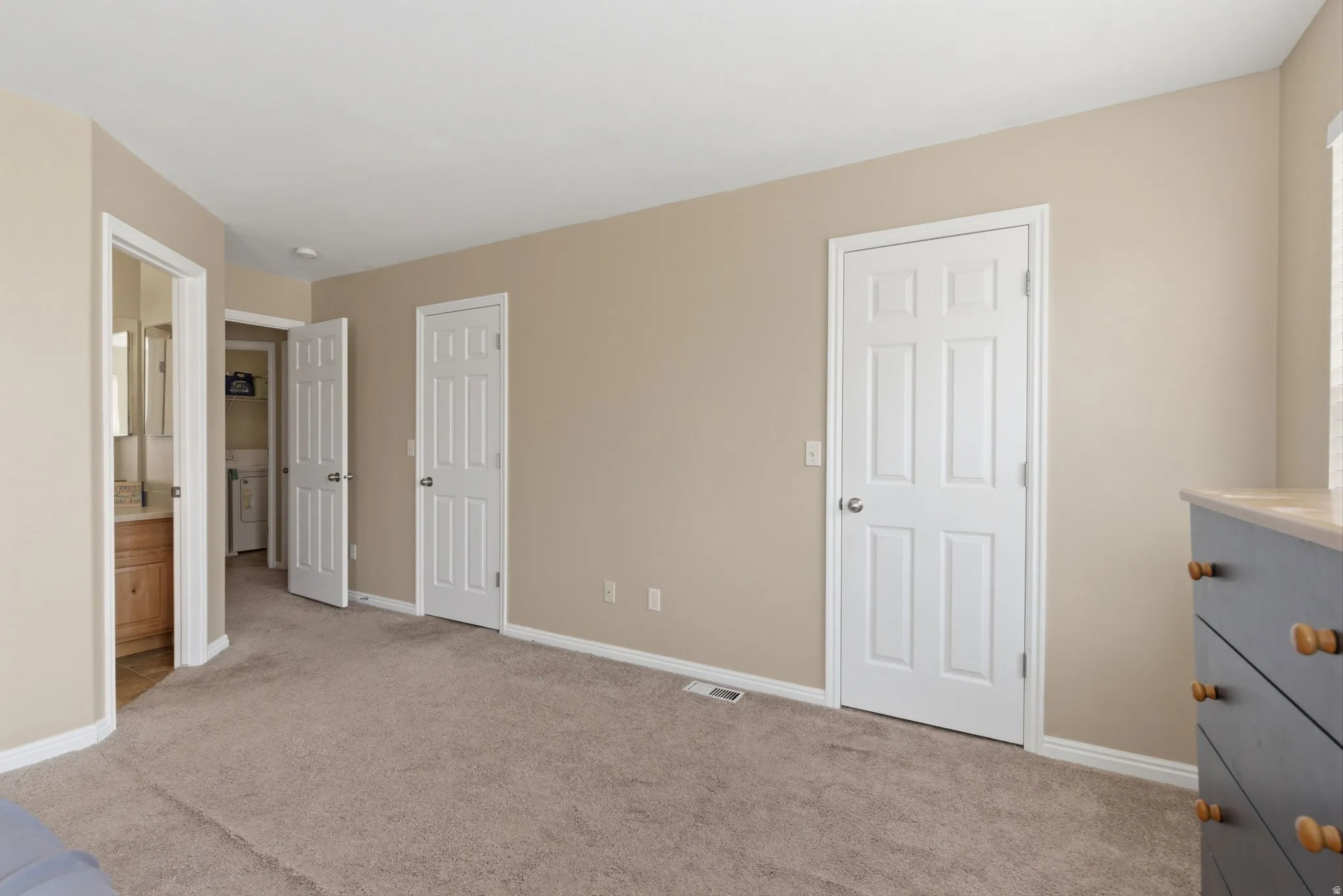 Unfurnished bedroom featuring light carpet and ensuite bath