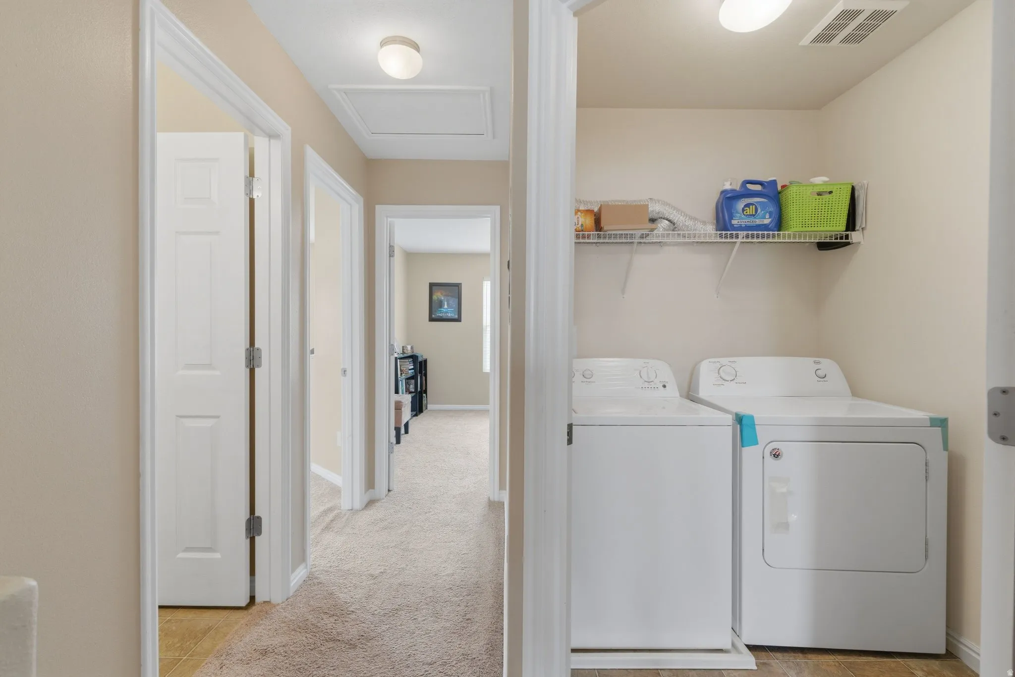 Laundry area with separate washer and dryer and light colored carpet
