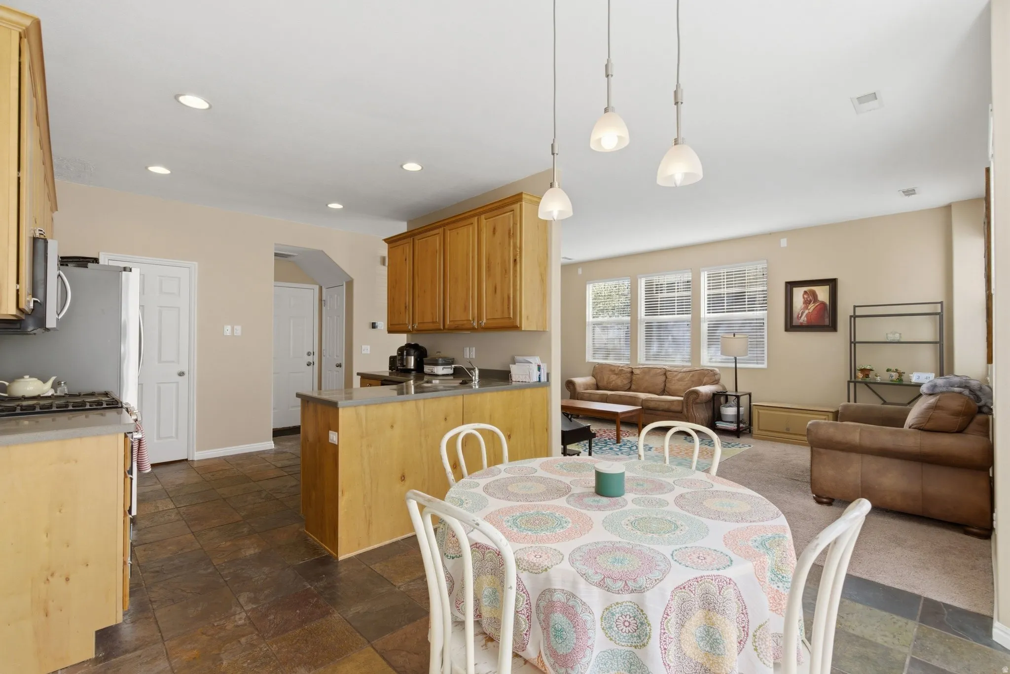 Dining room with stone tile flooring, arched walkways, and recessed lighting