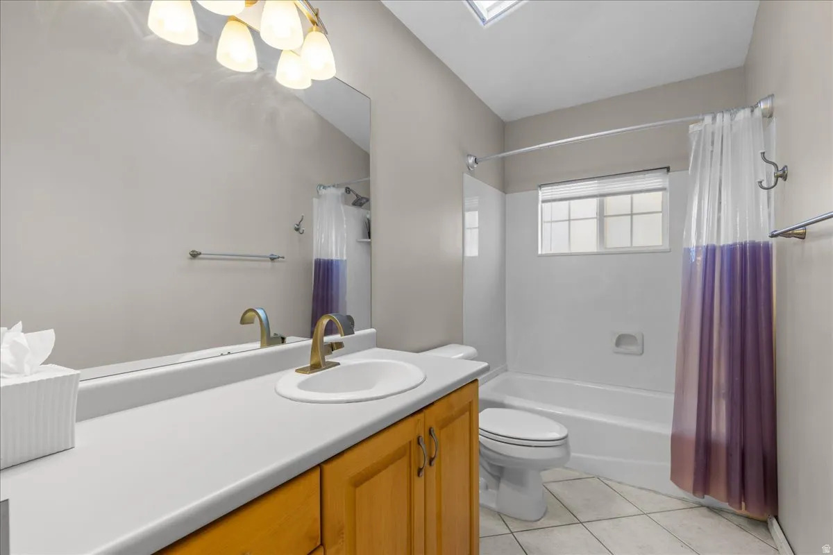 Bathroom with vanity, shower / tub combo, light tile patterned flooring, a skylight, and a chandelier