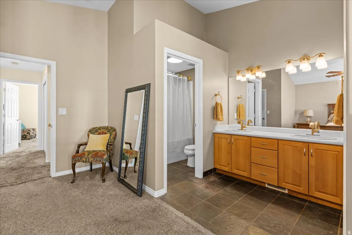 Bathroom featuring double vanity, dark colored carpet, and shower / bath combination with curtain