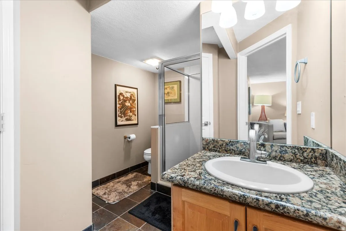 Ensuite bathroom with a shower stall, vanity, and dark tile patterned floors